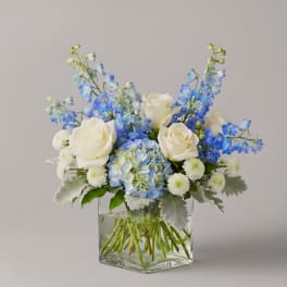 Blue and white floral arrangement in a clear square vase