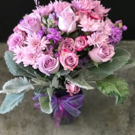 Pink and lavender bouquet of roses and chrysanthemums tied with a purple ribbon