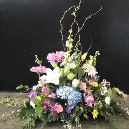 Large mixed floral arrangement with pink, white, blue, and yellow blooms