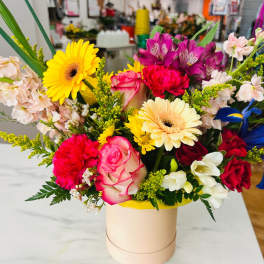Colorful mixed bouquet in a round box with roses and gerberas