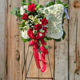 Standing floral heart wreath with red roses and white blooms on an easel