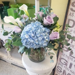 Blue hydrangea bouquet with lavender roses and white calla lilies in a glass vase