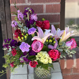 Mixed bouquet of pink, purple, and white flowers in a glass vase
