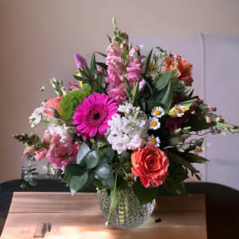 Mixed bouquet in a textured glass vase with pink, white, and orange blooms