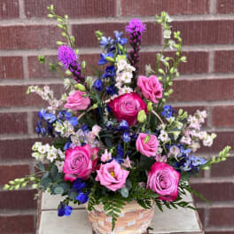 Mixed pink and blue flower arrangement in a woven basket