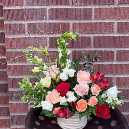 Mixed bouquet of roses, carnations, and white blooms in a white vase