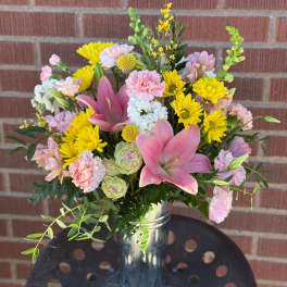 Pink lilies and yellow daisies in a metal vase