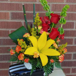 Floral arrangement in a toy car with red roses and a large yellow lily