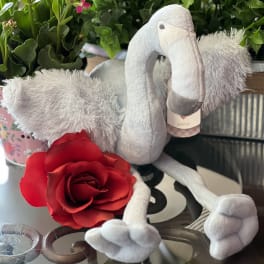 Plush flamingo with a red rose and potted flowering plant