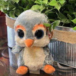 Plush penguin toy in front of potted greenery