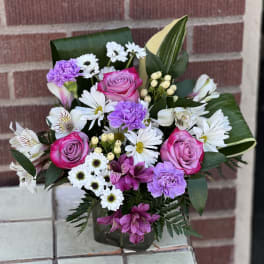 Bouquet of pink roses, white daisies, and purple carnations in a vase