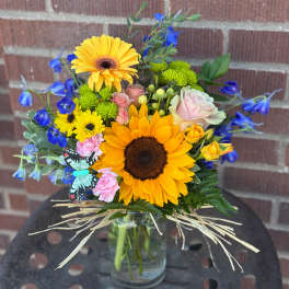 Sunflower bouquet with blue flowers in a glass vase