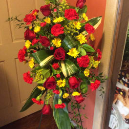Standing floral spray with red roses, red carnations, and yellow daisies