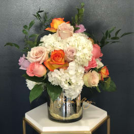 Mixed roses and white hydrangeas in a mirrored vase