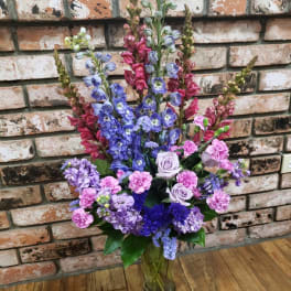 Tall bouquet of purple and pink flowers in a glass vase