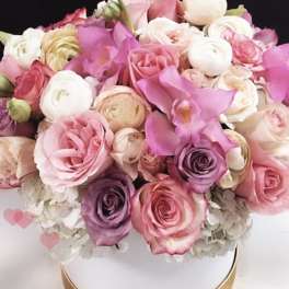 Pink and white roses with calla lilies in a round white box