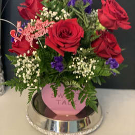 Red roses with purple filler flowers in a pink vase