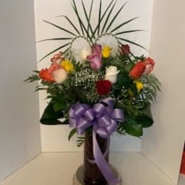 Mixed bouquet of roses with a purple ribbon in a vase