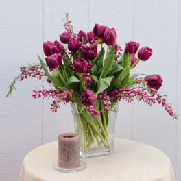 Magenta tulips in a clear glass vase with pink filler flowers