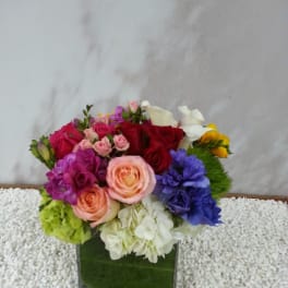 Colorful mixed bouquet in a square green vase