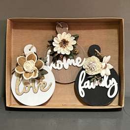 Three decorative wooden signs with faux flowers in a box