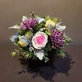 Small bouquet of purple, pink, yellow, and white flowers in a low container