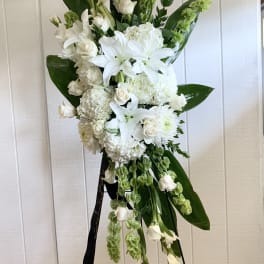 Tall white floral standing spray on an easel with lilies and roses