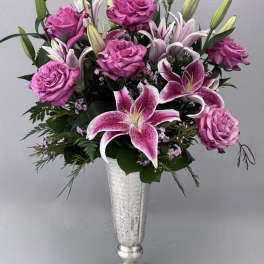 Pink roses and lilies arranged in a silver vase