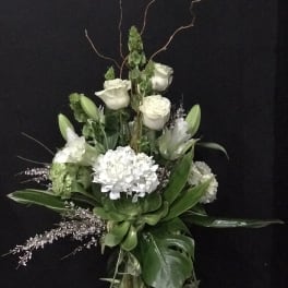 White floral arrangement with roses, lilies, and hydrangea in a tall vase