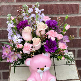 Pink teddy bear container holding a mixed bouquet of roses and carnations