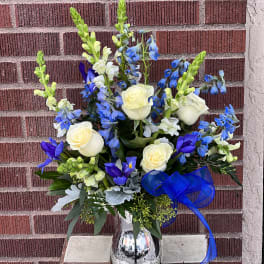Blue and white floral arrangement in a silver vase with a blue ribbon