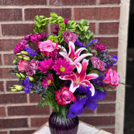 Pink and purple bouquet with lilies and roses in a purple vase