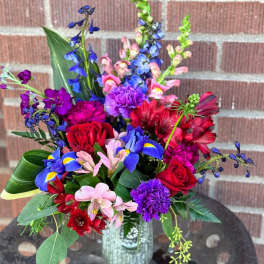 Colorful mixed bouquet with roses, irises, and alstroemeria in a glass vase