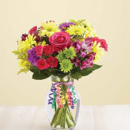Mixed bouquet of roses and daisies in a glass vase with colorful ribbon curls
