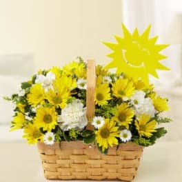 Yellow and white flowers in a woven basket with a sun decoration