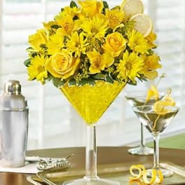 Yellow flower arrangement in a martini glass with lemon slices