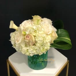 Cream rose and hydrangea arrangement in a green glass vase
