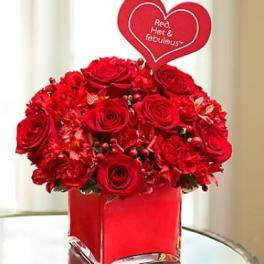 Red rose arrangement in a square red vase with a heart pick