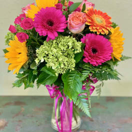 Bright mixed bouquet in a glass vase with pink, orange, and yellow blooms