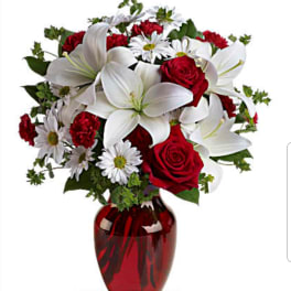Red roses and white lilies in a red glass vase