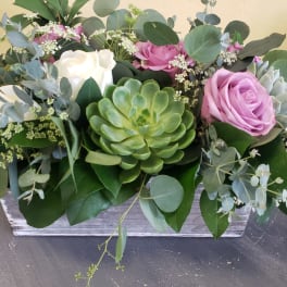 Arrangement of pink and white roses with a green succulent in a wooden box
