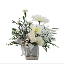 White flowers in a square glass vase with a silver ribbon
