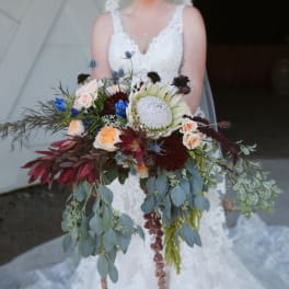Bride holding a large cascading bouquet with mixed flowers and greenery