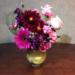 Bouquet of pink, purple, and burgundy flowers in a gold vase