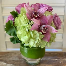 Pink orchids and green hydrangeas arranged in a glass vase