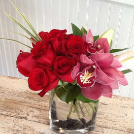 Red roses and pink orchids in a clear glass vase
