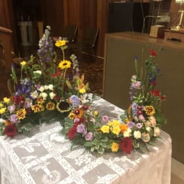 Colorful floral arrangements on a lace-covered table in a church interior