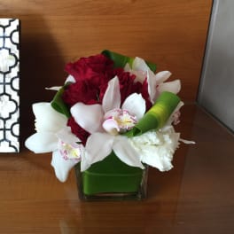 Bouquet of red and white flowers in a square glass vase