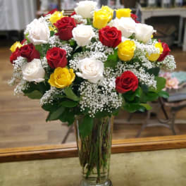 Bouquet of red, white, and yellow roses in a clear glass vase