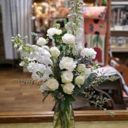 Tall white floral arrangement in a clear glass vase